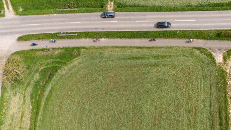 An aerial view shows cyclists riding along a road near Ohlsbach, on which two cars can be seen. According to provisional figures, there has been a new nationwide heat record for the first ten days of April since weather records began: Yesterday, Saturday, 30.1 degrees were measured in Ohlsbach in the Rhine Valley, according to a spokesperson for the German Weather Service. Philipp von Ditfurth/dpa