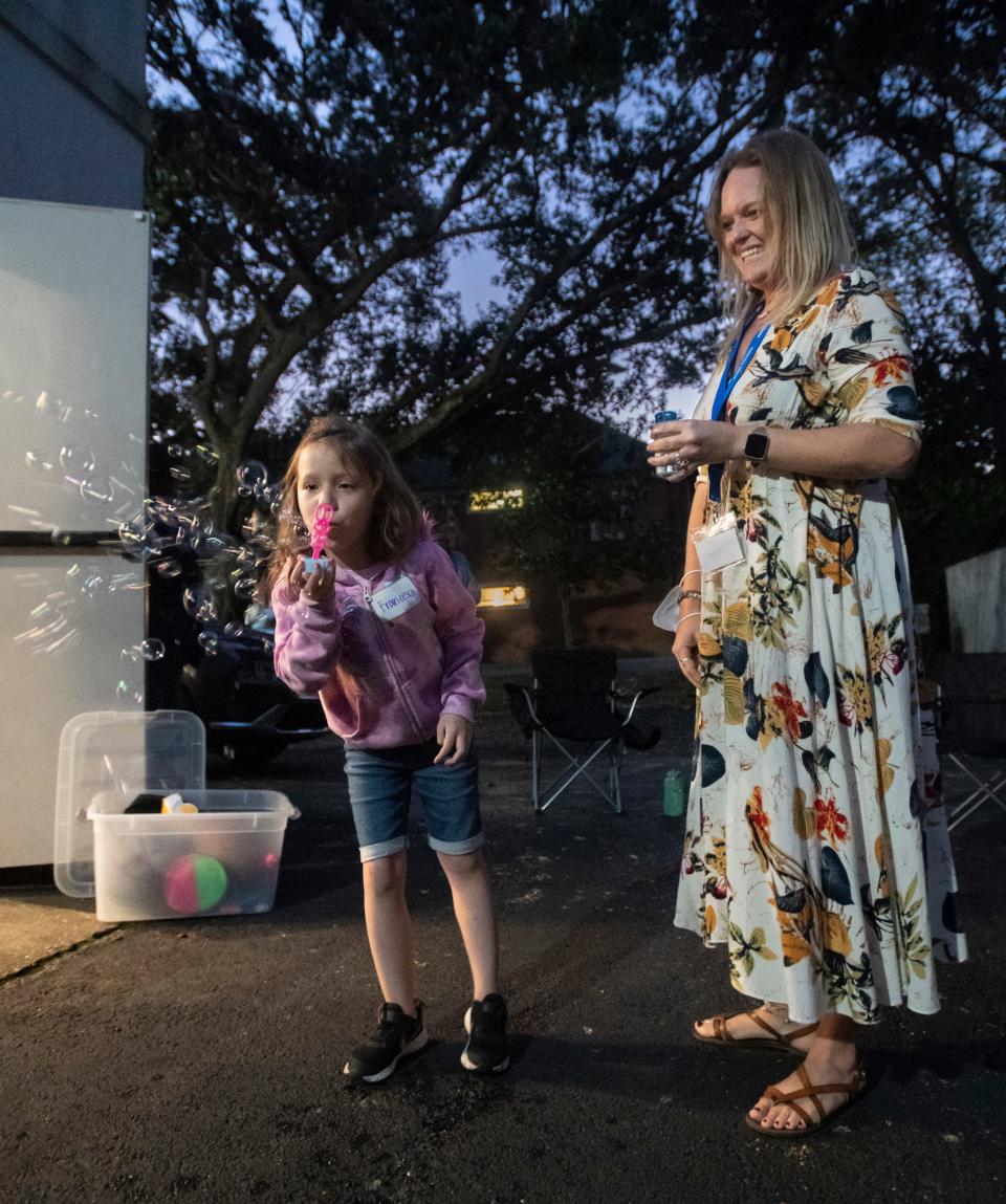 Volunteer Jennifer Elzweig looks on as Francesca Pease, 7, who lost her mother Charity Pease, blows bubbles prior to the Valerie's House group night “What I Hate About Death” activity hosted at the Big Brothers Big Sisters of Northwest Florida building in Pensacola on Tuesday, Nov. 2, 2021.