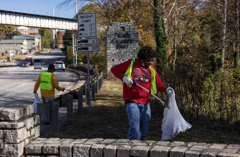 John Dye, 42, and Randy Jones, 24, right, walk along the intersection of North Avenue and Willow Street picking up trash as part of A Safe and Clean Athens program on Friday, Nov. 12, 2021. It provides a positive way for those in the homeless community to make some money, instead of doing something negative, Jones said of Sparrow’s Nest’s program.