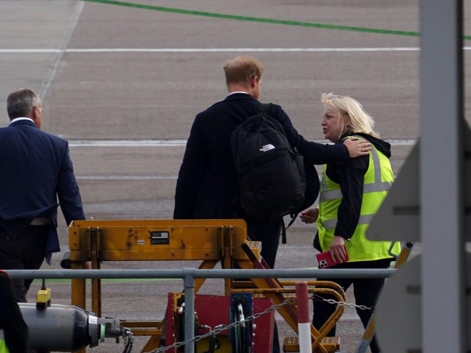 Prince Harry puts his hand on traffic contoller's arm at at Aberdeen Airport on September 9, 2022 in Aberdeen, United Kingdom.