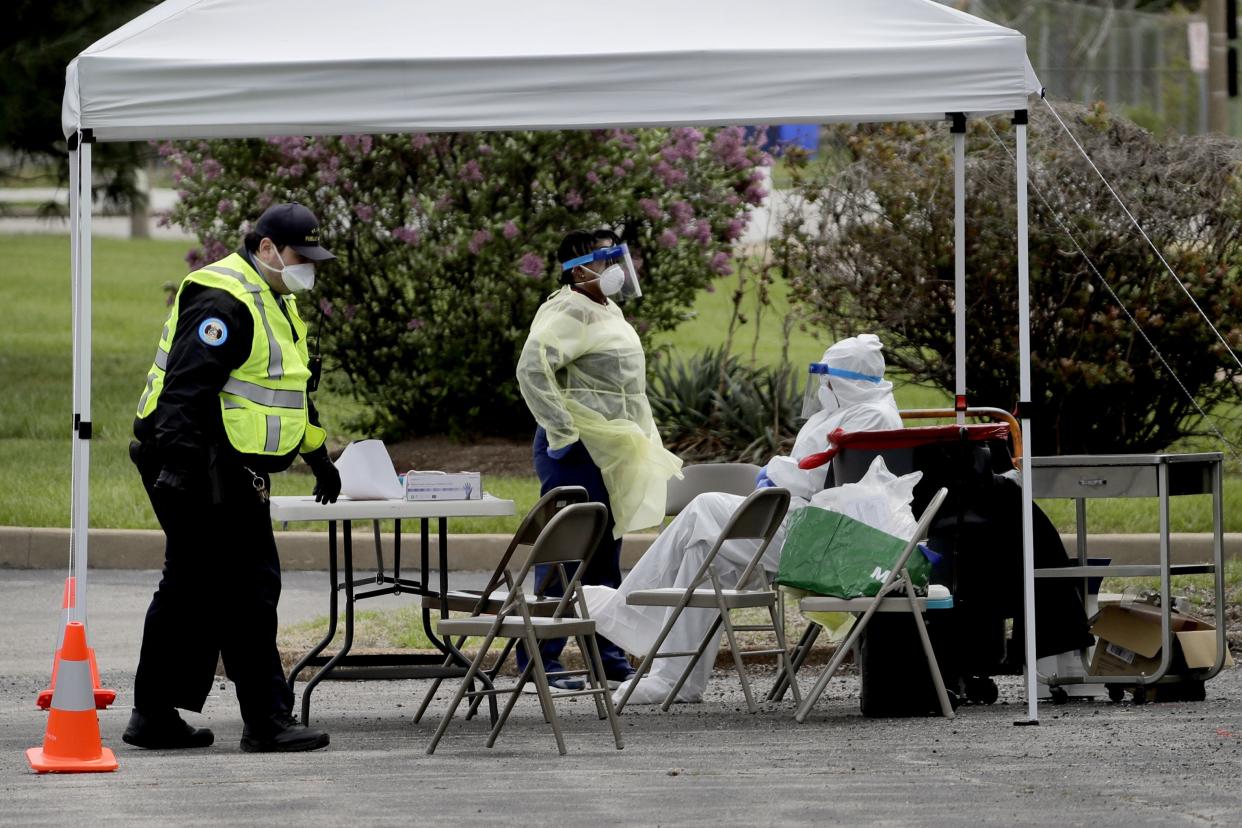 Health care workers and security personnel wait for patients at a drive-up COVID-19 testing location on Monday, April 13, 2020, where the coronavirus outbreak is taking a disproportionate toll in a predominately black area of St. Louis, Missouri.