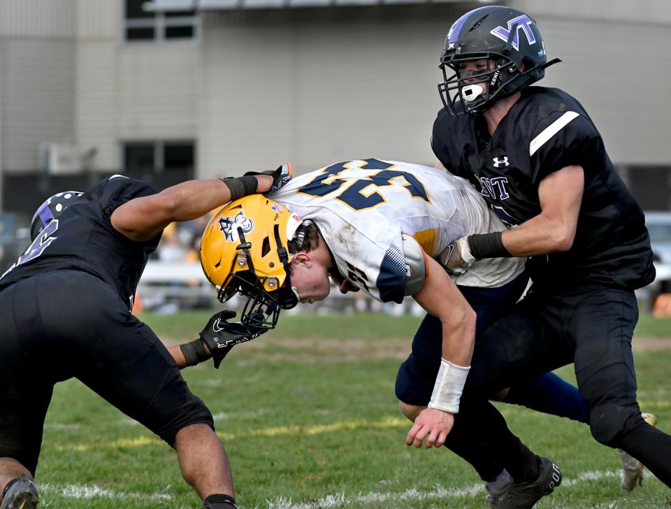 Arlington Catholic quarterback Thomas Driscoll, center, almost loses his helmet as Blackstone Valley Tech's Jayden Roderigues, left, and Jordan St. Pierre make the tackle in the first half of Saturday's game.