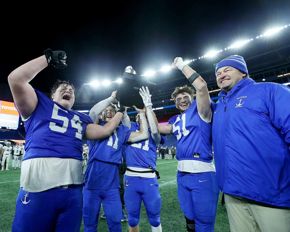 Scituate’s Michael Sheskey, Andrew Bossey, Keegan Sullivan, John Thompson and head coach Herb Devine celebrate with their newly earned hardware following a 14-13 win over Duxbury in the Division 4 state title game at Gillette Stadium in Foxboro on Friday, Dec. 3, 2021.