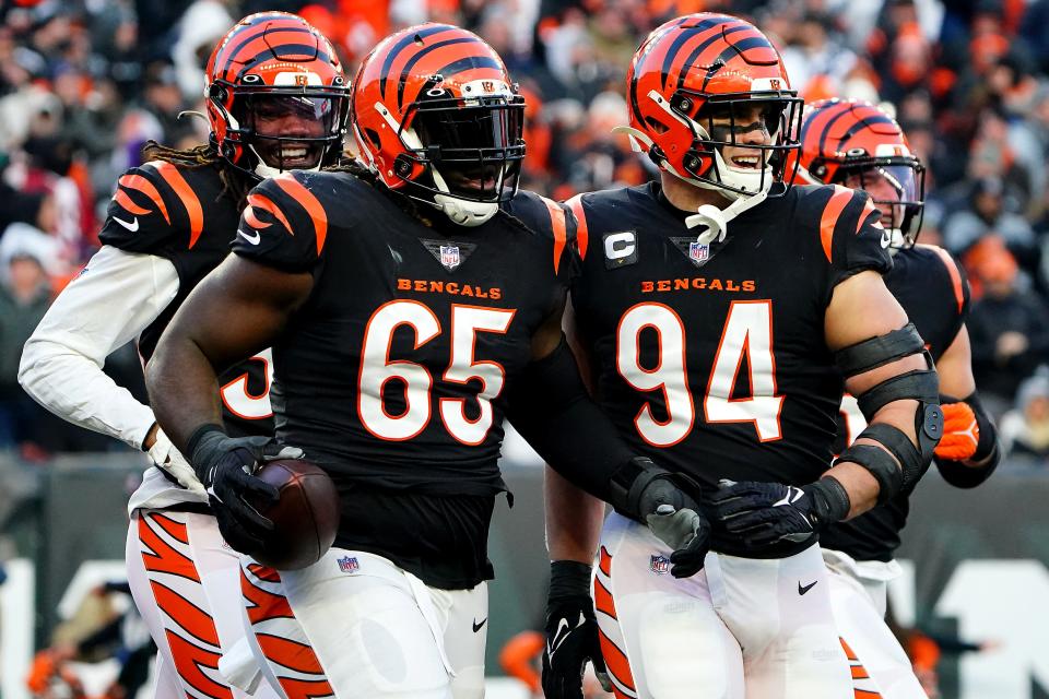 Cincinnati Bengals defensive tackle Larry Ogunjobi (65) is congratulated by Cincinnati Bengals defensive end Sam Hubbard (94) as he returns to the bench after recovering a fumble in the first quarter during an NFL AFC wild-card playoff game against the Las Vegas Raiders, Saturday, Jan. 15, 2022, at Paul Brown Stadium in Cincinnati.