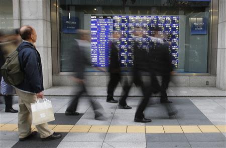 A man looks at a stock quotation board as passers-by walk past, outside a brokerage in Tokyo December 4, 2013. REUTERS/Toru Hanai