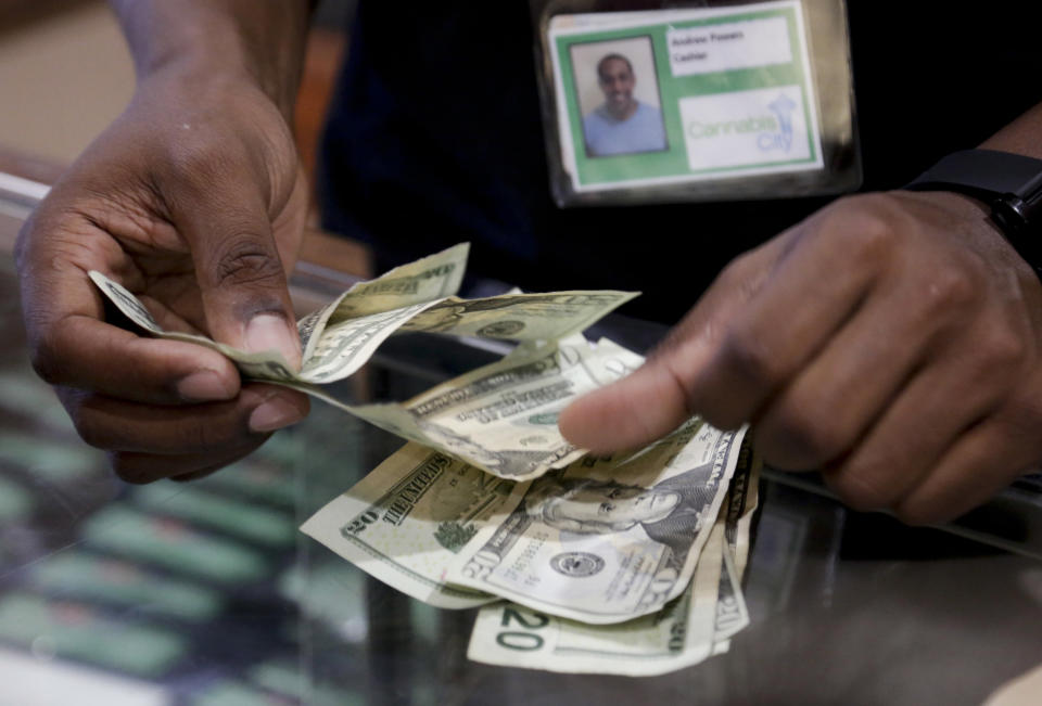 Cashier Andrew Powers completes a cash marijuana purchase at Cannabis City during the first day of legal retail marijuana sales in Seattle, Washington July 8, 2014. Washington became the second U.S. state to allow the sale of marijuana for recreational use on Tuesday, although shortages and high prices are likely to accompany any euphoria. Shops started to open on Tuesday, a day after 25 outlets were issued licenses under a heavily regulated and taxed system approved by voters in November 2012. REUTERS/Jason Redmond   (UNITED STATES - Tags: SOCIETY DRUGS BUSINESS)