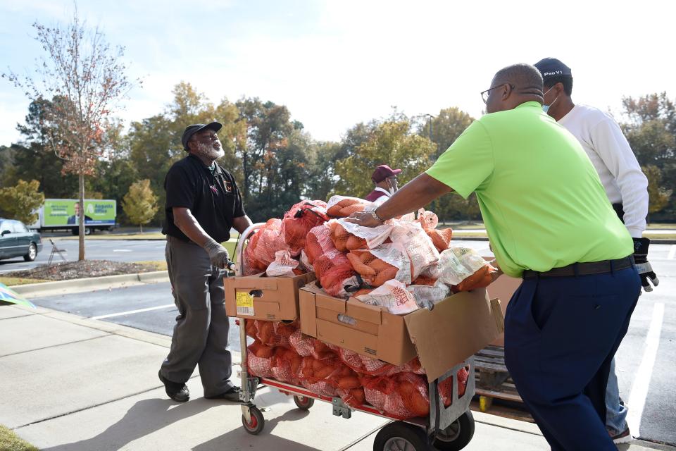 Garnett Johnson (right) helps volunteers load extra sweet potatoes he donated onto a trolley for a turkey giveaway at Good Shepherd Baptist Church on Thursday, Nov. 18, 2021. Johnson is a member of the church.
