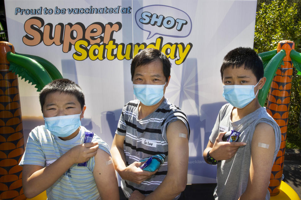 Johnson, left, Bailou, center, and Benson Su of Auckland show their patches after receiving their vaccination in Auckland, New Zealand, Saturday, Oct. 16, 2021. New Zealand health care workers have administered a record number of vaccine jabs as the nation holds a festival aimed at getting more people inoculated against the coronavirus. (Brett Phibbs/NZME via AP)