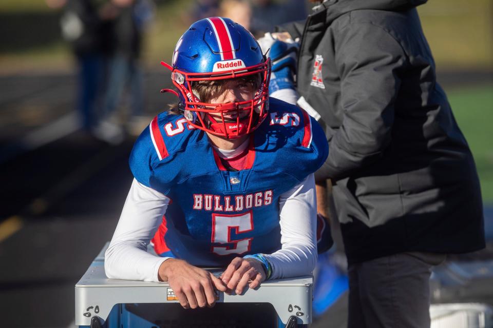 A medical team member checks Mason quarterback Cason Carswell's leg during the game against Detroit King at Chelsea High School on Saturday, Nov. 18, 2023.