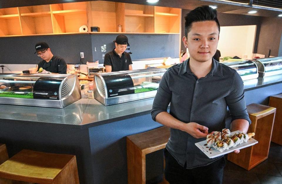 Guan Wu, manager at Tsukiji Japanese Cuisine in north Fresno, holds a Crazy Roll sushi dish, one of the restaurant’s more popular items, as chefs prepare orders for customers on Monday, May 13, 2024.