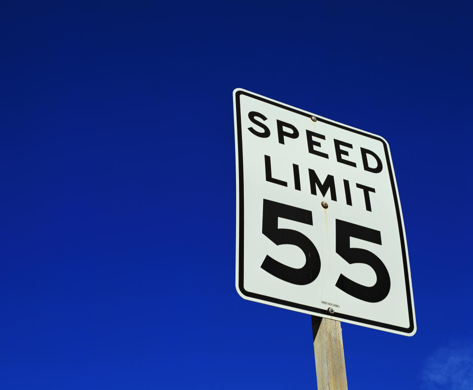 A speed limit sign showing "55" against a clear sky