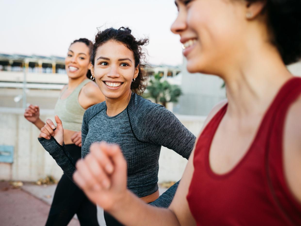 Three women smiling and running together