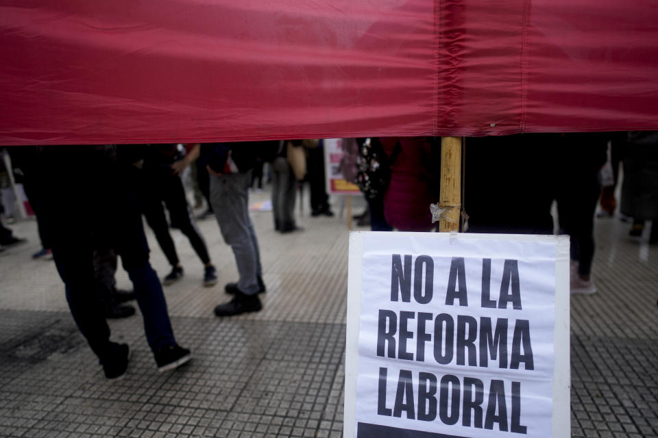 Anti-government protesters stand with a sign that reads in Spanish "No to the labor law reform" outside Congress where lawmakers debate a bill promoted by Argentine President Javier Milei that includes a broad range of economic, administrative, criminal and environmental reforms in Buenos Aires, Argentina, Tuesday, April 30, 2024. (AP Photo/Natacha Pisarenko)