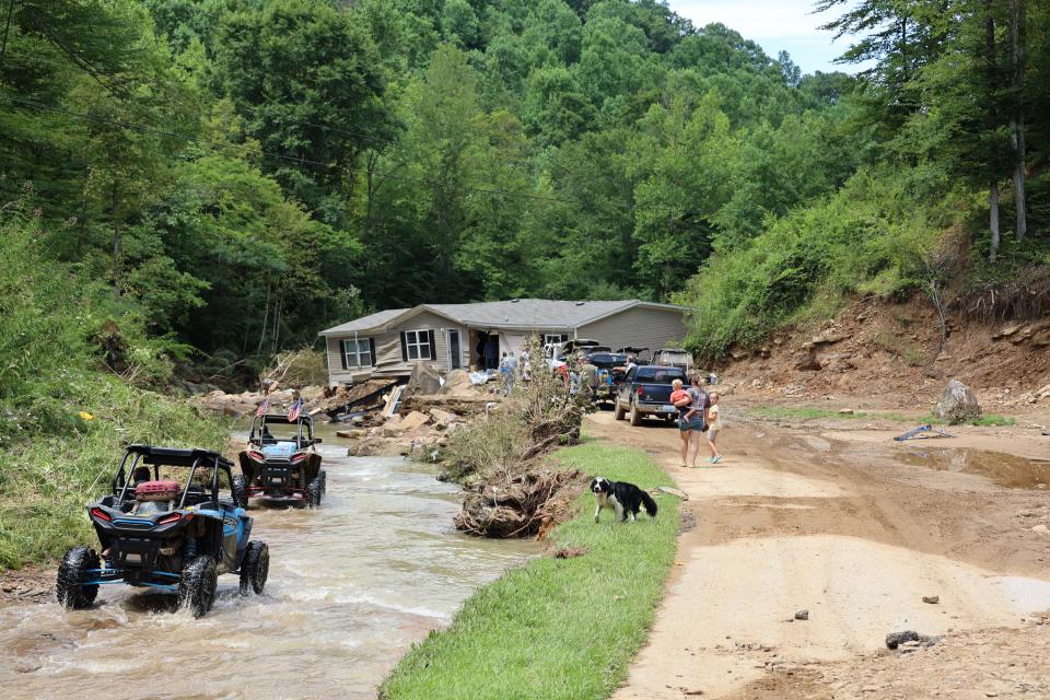 ATV drivers ferry generator fuel and water around Jessica Willett's home in Bowling Creek, Ky. Flooding tore it from its foundations and left it in the middle of the road.
