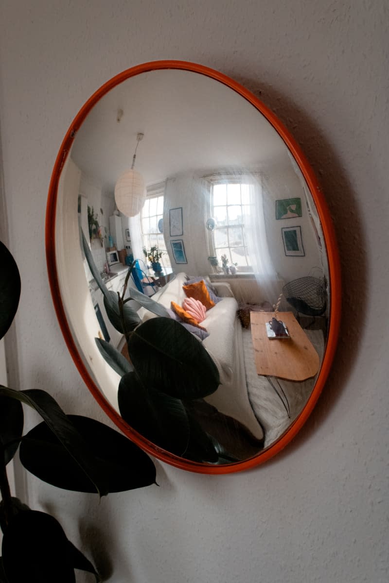 Convex mirror reflecting the view of the living room.