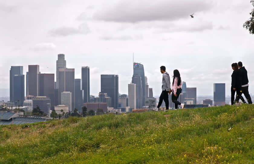 LOS ANGELES, CA - APRIL 13: Romell and Gloria Anthopoulos, left, and Anthony Riodriguez with Rosa Andrade, right, enjoy a walk through Elysian Park with a view of downtown Los Angeles on a cloudy Monday as it appears most people are staying home due to the coronavirus Covid-19 pandemic Los Angeles on Monday, April 13, 2020 in Los Angeles, CA. (Al Seib / Los Angeles Times)