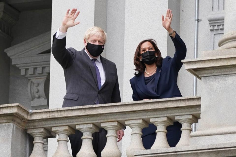 Boris Johnson and vice president Kamala Harris wave from a balcony of the Eisenhower Executive Office Building (PA)