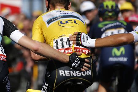 Etixx-Quick Step rider Tony Martin of Germany (C), race leader's yellow jersey, is supported by team mates Julien Vermote of Belgium and Michal Kwiatkowski of Poland after a fall during the 191.5-km (118.9 miles) 6th stage of the 102nd Tour de France cycling race from Abbeville to Le Havre, France, July 9, 2015. REUTERS/Benoit Tessier