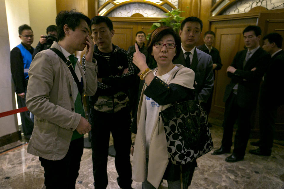 Relatives of Chinese passengers aboard the missing Malaysia Airlines flight MH370 at left and right speak with a person in charge of security to give journalists access to a meeting in Beijing, China, Monday, March 24, 2014. Rain was expected to hamper the hunt Monday for debris suspected of being from the missing Malaysia Airlines jet, as the United States prepared to move a specialized device that can locate black boxes into the south Indian Ocean region. (AP Photo/Ng Han Guan)