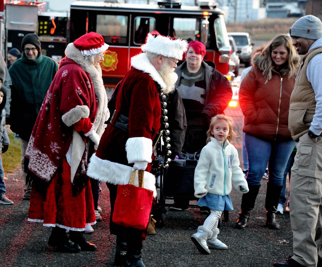 A young girl takes a good look at Mr. and Mrs. Claus as they walk through the crowd of people during Home for the Holidays in Orrville on Friday night.