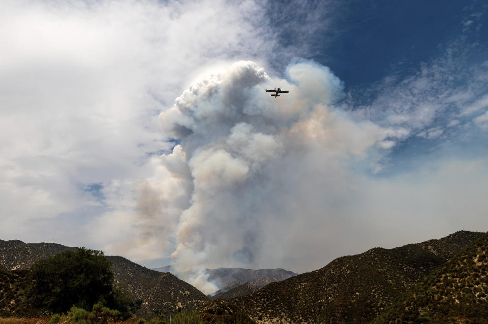 A super scooper water-dropping aircraft passes a plume of smoke as the Lake Fire burns in the Angeles National Forest north of Santa Clarita, Calif., on Thursday, Aug. 13, 2020. (AP Photo/Noah Berger)