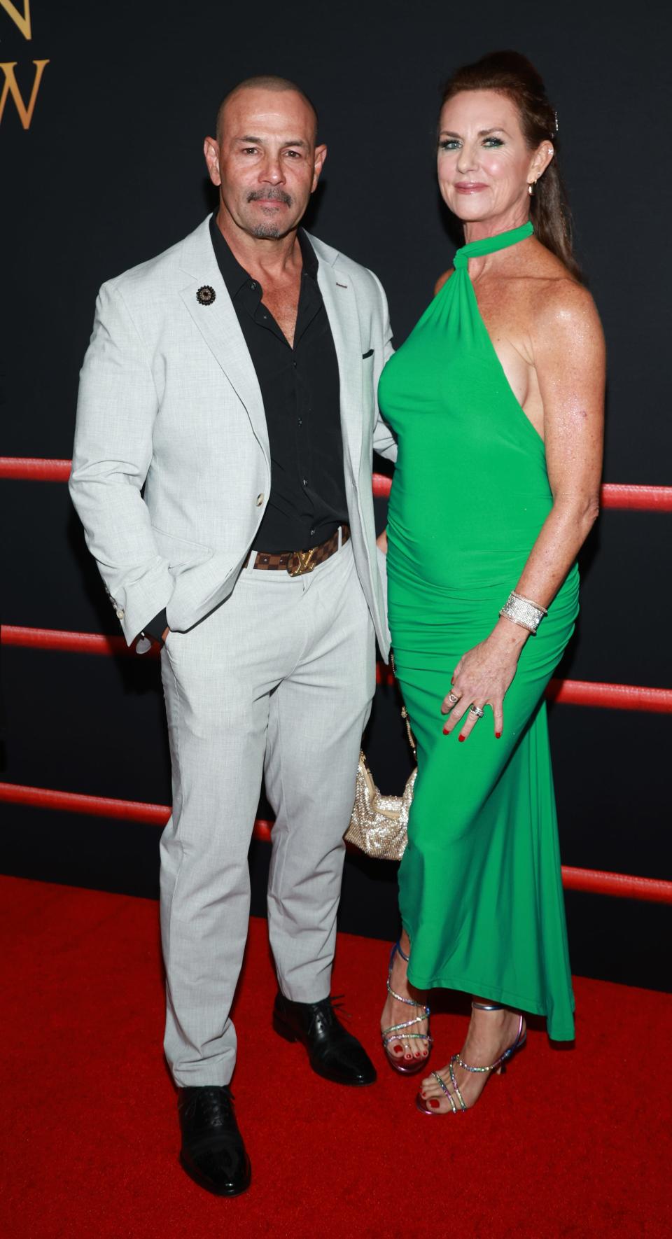 Chavo Guerrero Jr. in a white suit and his wife Susan Guerrero in a green dress at "The Iron Claw" premiere