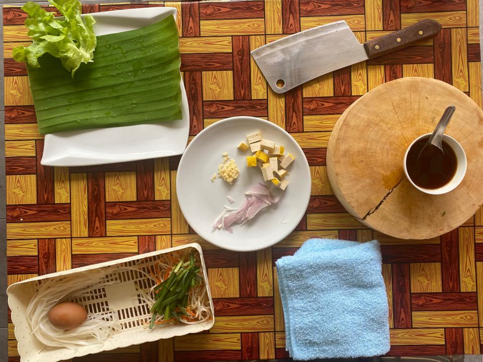 plates of food and cooking supplies laid artfully on a wooden table at a cooking class in Thailand