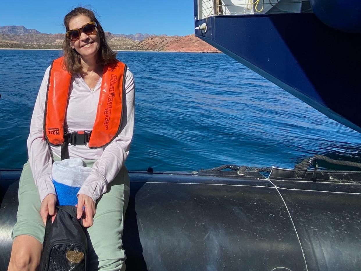 A woman wearing a life jacket sits on the side of an inflatable boat.