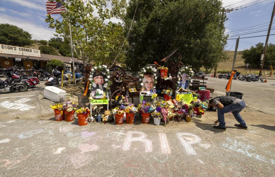 A man writes a message in chalk at a memorial.