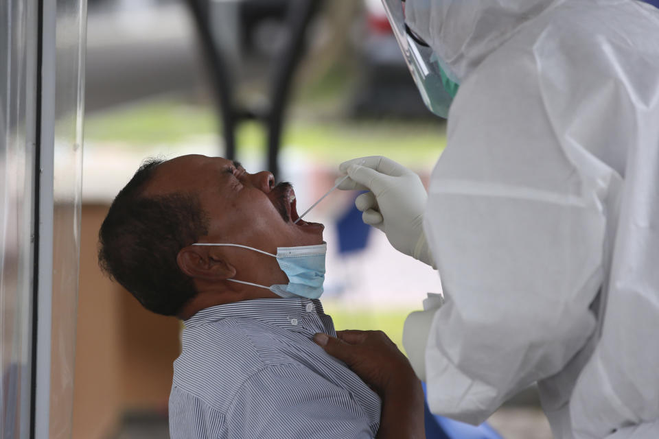 A man reacts as a medical workers collect his nasal swab samples to be tested for coronavirus, during a COVID-19 screening at University of North Sumatra in Medan, Indonesia, Monday, June 21, 2021. Indonesia has reported more coronavirus cases than any other country in Southeast Asia. (AP Photo/Binsar Bakkara)