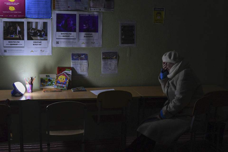 A woman sits at a school building, a "Point of Invincibility," a government-built help station that serves food, drinks and the possibility to warm up, in Kramatorsk, Ukraine, Monday, Dec. 5, 2022. (AP Photo/Andriy Andriyenko)