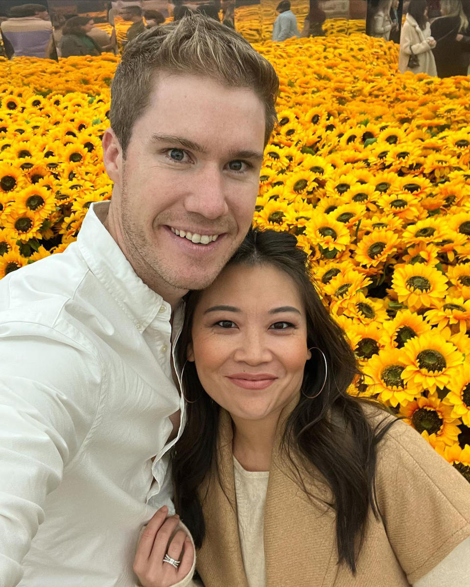 Liam and Tracy smile for a selfie in front of a sea of artificial sunflowers