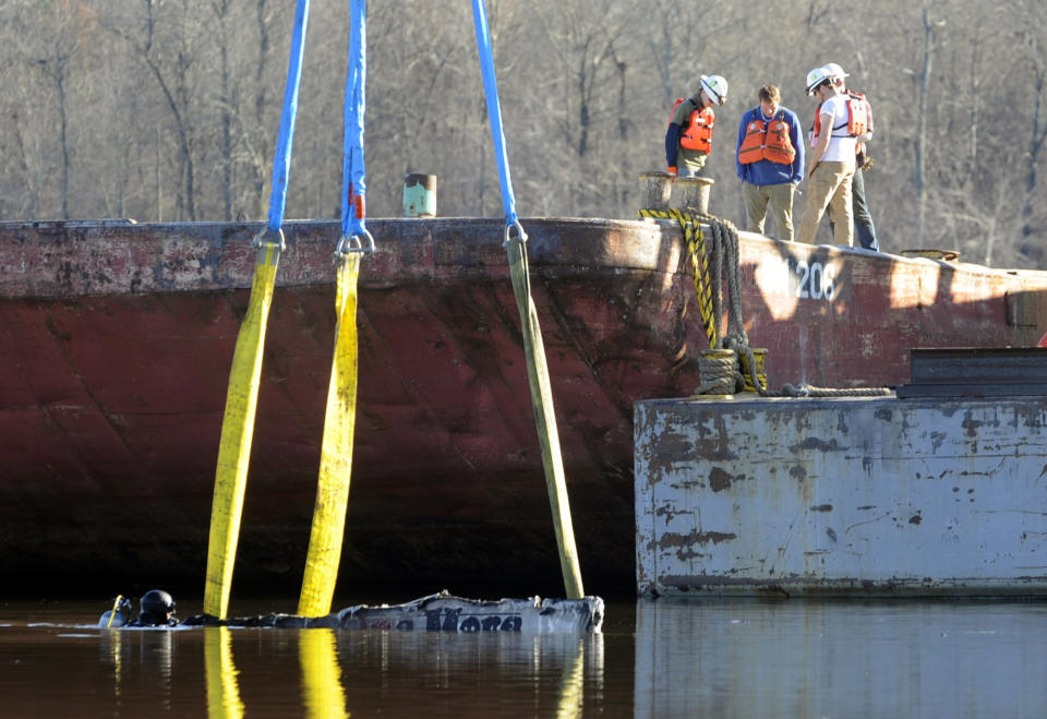 A diver works in the water as a crane attempts to lift the remains of a burned boat in Scottsboro, Ala., on Tuesday, Jan. 28, 2020, following a dock fire that killed eight people. Sunken in a creek that feeds into the Tennessee River, officials said the craft was one of about 35 that were engulfed in flames. (AP Photo/Jay Reeves)