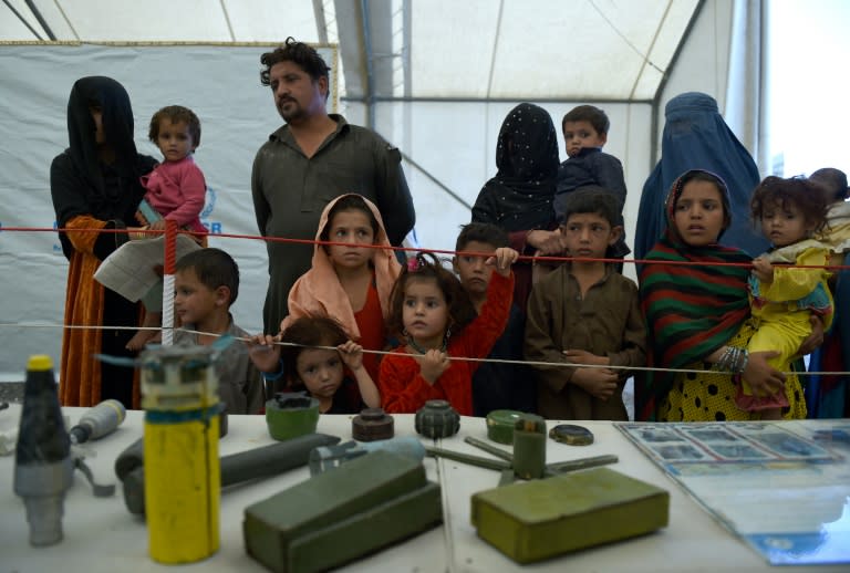 Afghan refugee families look at samples of bombs and mines at the United Nations High Commissioner for Refugees (UNHCR) camp on the outskirts of Kabul on September 27, 2016