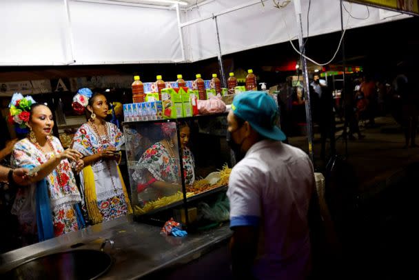 PHOTO: Women wearing traditional dresses order food, close to where section 2 of the new Mayan Train route is being built, in Tenabo, Campeche, Mexico, May 13, 2022. (Jose Luis Gonzalez/Reuters)