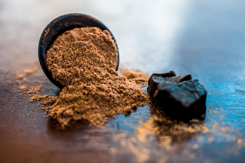 Raw organic hing or devil's dung along with some dried ginger on wooden surface and powder of giant fennel in a clay bowl  along with some mint leaves,Close up view or shot.