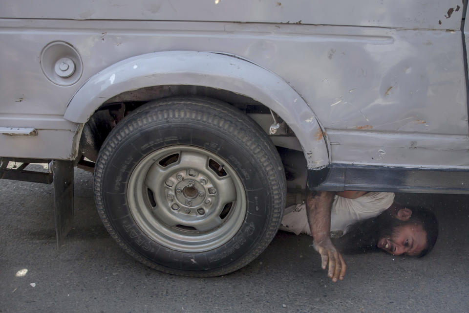 FILE - In this Friday, June 1, 2018, file photo, a Kashmiri man shouts for help as a paramilitary vehicle runs over him during a protest in Srinagar, Indian controlled Kashmir. The region is one of the most heavily militarized in the world, patrolled by soldiers and paramilitary police. Most Kashmiris resent the Indian troop presence and support the rebels. For years, there have been accusations from Kashmir residents and international human rights groups that Indian troops have carried out systematic abuse and unjustified arrests of those who oppose rule from New Delhi in the divided region that is claimed by both India and Pakistan. (AP Photo/Dar Yasin)