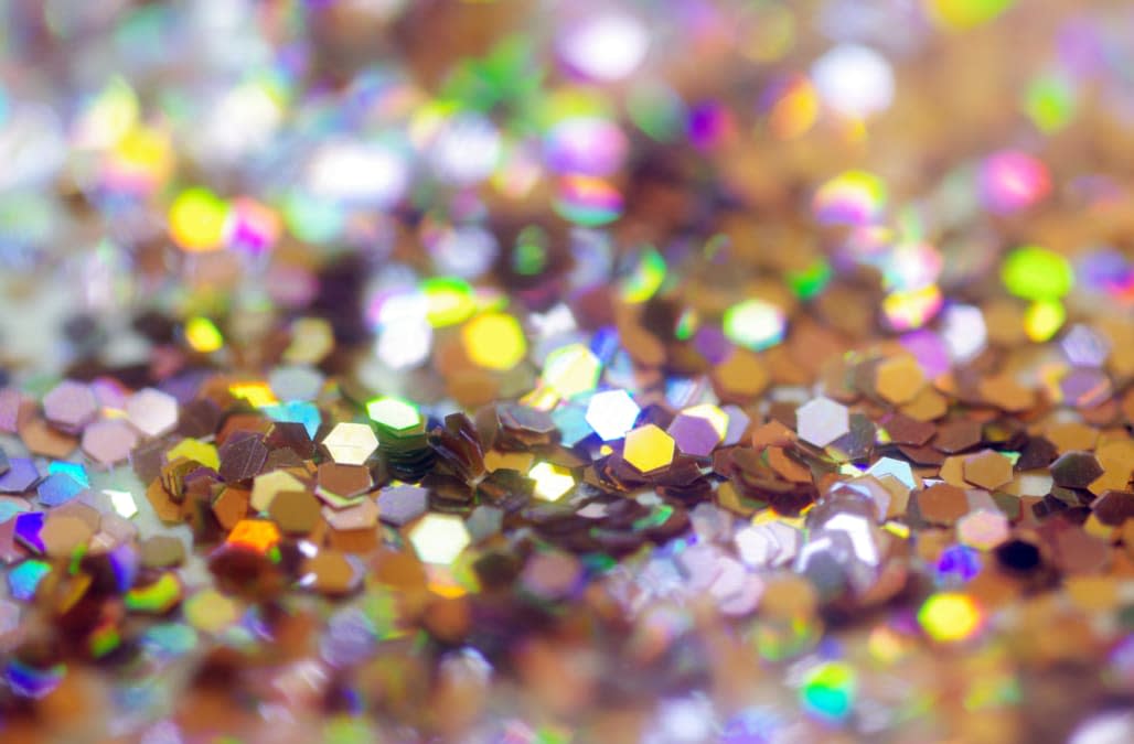 Close-up of silver glitter reflecting colors of the rainbow. Selective focus for bokeh effect.