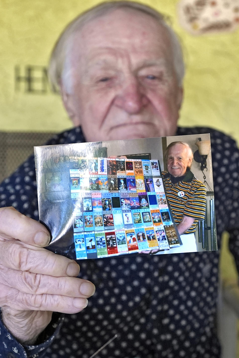 Tom Henschel holds up a photo of 50-yards of Super Bowl tickets during an interview at his home Thursday, Jan. 25, 2024, in Tampa, Fla. Three football fans in their 80s are keeping their membership in the "never missed a Super Bowl" club. (AP Photo/Chris O'Meara)