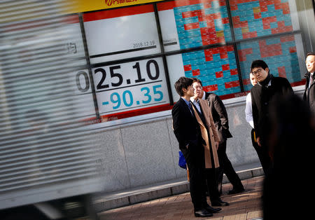 FILE PHOTO: Men stand in front of a stock quotation board outside a brokerage in Tokyo, Japan December 19, 2018. REUTERS/Issei Kato