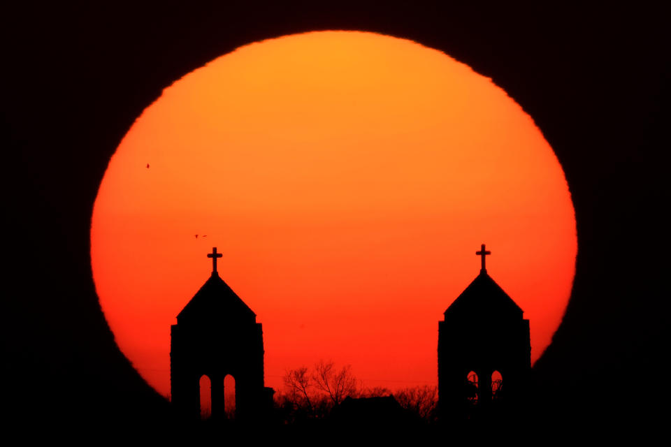 FILE - The sun sets beyond the twin steeples of the Hosanna Karen Baptist church Wednesday, March 29, 2023, in Kansas City, Kan. In the year since the Supreme Court struck down the nationwide right to abortion, America’s religious leaders and denominations have responded in strikingly diverse ways _ some celebrating the state-level bans that have ensued, others angered that a conservative Christian cause has changed the law of the land is ways they consider oppressive. (AP Photo/Charlie Riedel, File)