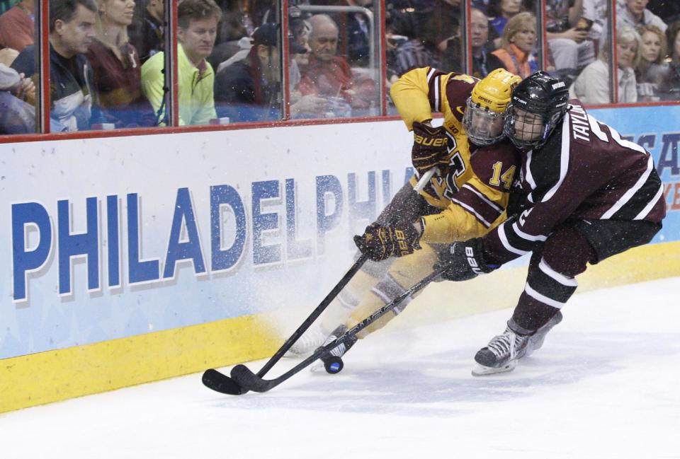 Minnesota's Tom Serratore, left, and Union's Jeff Taylor, right, battle for the puck along the boards during the second period of an NCAA men's college hockey Frozen Four tournament game on Saturday, April 12, 2014, in Philadelphia. (AP Photo/Chris Szagola)