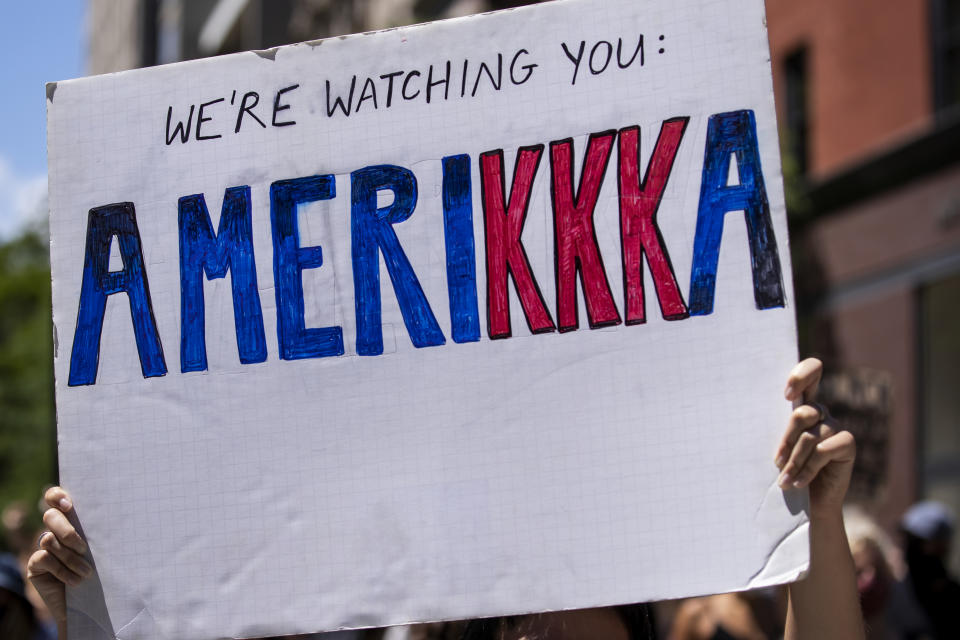 MANHATTAN, NY - JUNE 12:  A protester holds a homemade sign that says, "We're Watching You Amerikka" with the letters of the kkk in red during a protest with hundreds of people that marched in the streets to Gracie Mansion. This was part of the Black Womxn's Empowerment March that started at Trump Tower and marched to Gracie Mansion. Protesters continue taking to the streets across America and around the world after the killing of George Floyd at the hands of a white police officer Derek Chauvin that was kneeling on his neck during for eight minutes, was caught on video and went viral.  During his arrest as Floyd pleaded, "I Can't Breathe". The protest are attempting to give a voice to the need for human rights for African American's and to stop police brutality against people of color.  They are also protesting deep-seated racism in America.   Many people were wearing masks and observing social distancing due to the coronavirus pandemic.  Photographed in the Manhattan Borough of New York on June 12, 2020, USA.  (Photo by Ira L. Black/Corbis via Getty Images)