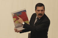 Erkan Bas, a lawmaker of the opposition Workers' Party, shows a map of divided Libya before Turkey's parliament authorized the deployment of troops to Libya to support the U.N.-backed government in Tripoli battle forces loyal to a rival government that is seeking to capture the capital, in Ankara, Turkey, Thursday, Jan. 2, 2020. Turkish lawmakers voted 325-184 at an emergency session in favor of a one-year mandate allowing the government to dispatch troops amid concerns that Turkish forces could aggravate the conflict in Libya and destabilize the region.(AP Photo/Burhan Ozbilici)