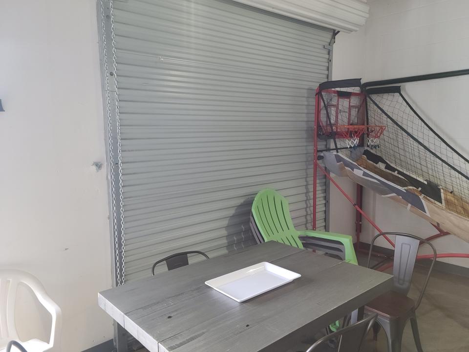 A green lawn chair in front of a garage door in the interior of a warehouse Aibnb