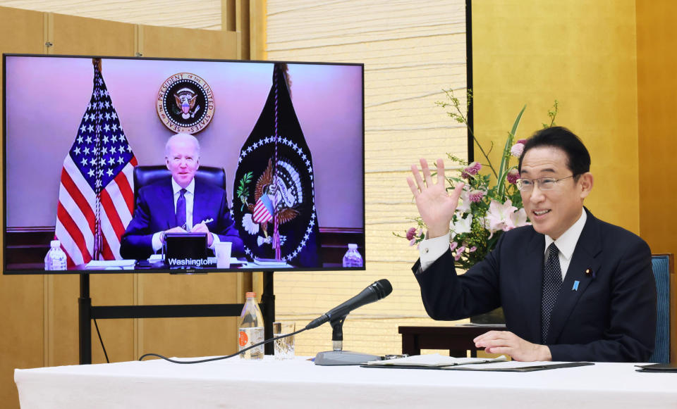 Japanese Prime Minister Fumio Kishida, right, sitting in a room of the prime minister's official residence in Tokyo, Friday, Jan. 21, 2022, talks in a virtual meeting with U.S. President Joe Biden, shown in the monitor. Biden and Kishida on Friday used their first formal meeting to discuss concerns about China's growing military assertiveness that's spurring increasing disquiet in the Pacific. (Cabinet Secretariat/Kyodo News via AP)