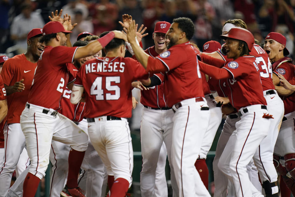 Teammates greet Washington Nationals' Joey Meneses (45) at home plate after he hit a three-run home run in the 10th inning of a baseball game against the Oakland Athletics, Thursday, Sept. 1, 2022, in Washington. Washington won 7-5. (AP Photo/Patrick Semansky)