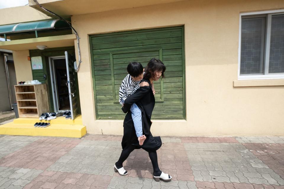 A woman carries a student who was slightly burnt by hot soup on her back.