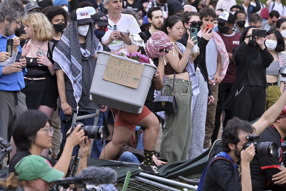 A demonstrator carries supplies over breached barriers to join a pro-Palestinian encampment, Monday, May 6, 2024, in at MIT in Cambridge, Mass. (AP Photo/Josh Reynolds)