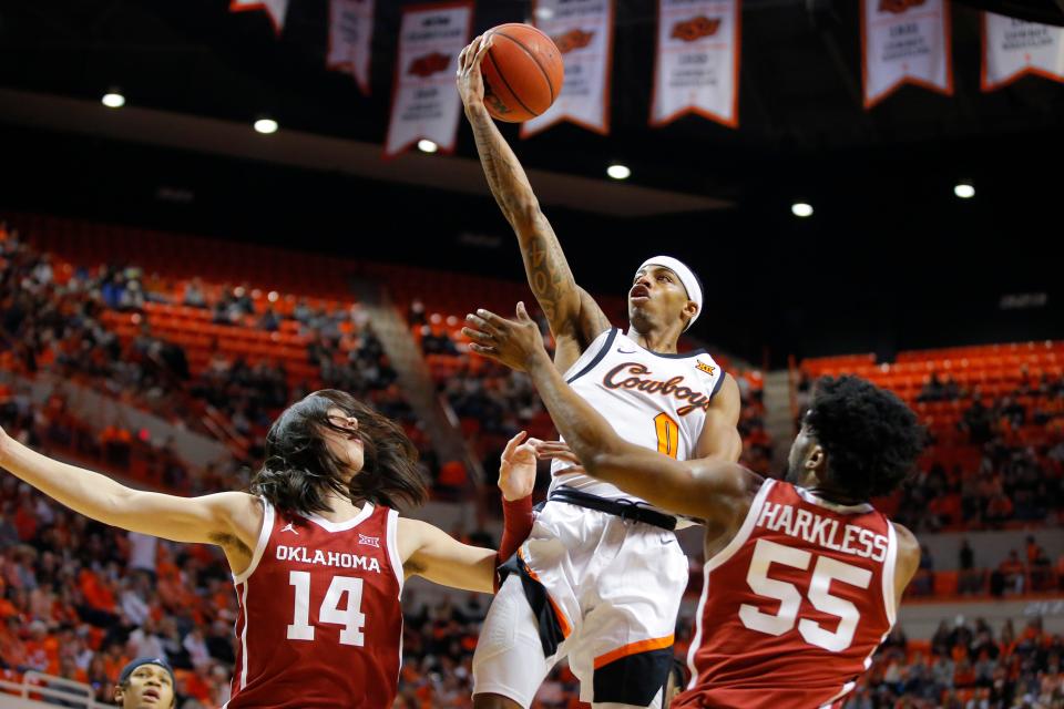 Oklahoma State Cowboys guard Avery Anderson III (0) goes to the basket between Oklahoma Sooners guard Bijan Cortes (14) and guard Elijah Harkless (55) during a Bedlam basketball game between the University of Oklahoma Sooners (OU) and the Oklahoma State University Cowboys (OSU) at Gallagher-Iba Arena in Stillwater, Saturday, Feb. 5, 2022. 